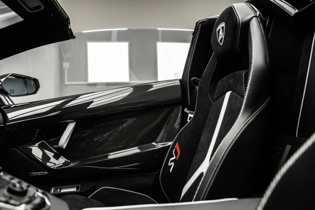 Carbon-fibre door panel and black Alcantara seat inside a Lamborghini supercar